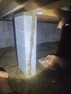Termite mud tube running up a support pier beneath a home